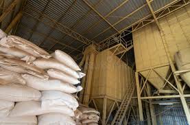 Stockfeed mill interior — stacked feed sacks beside grain silos